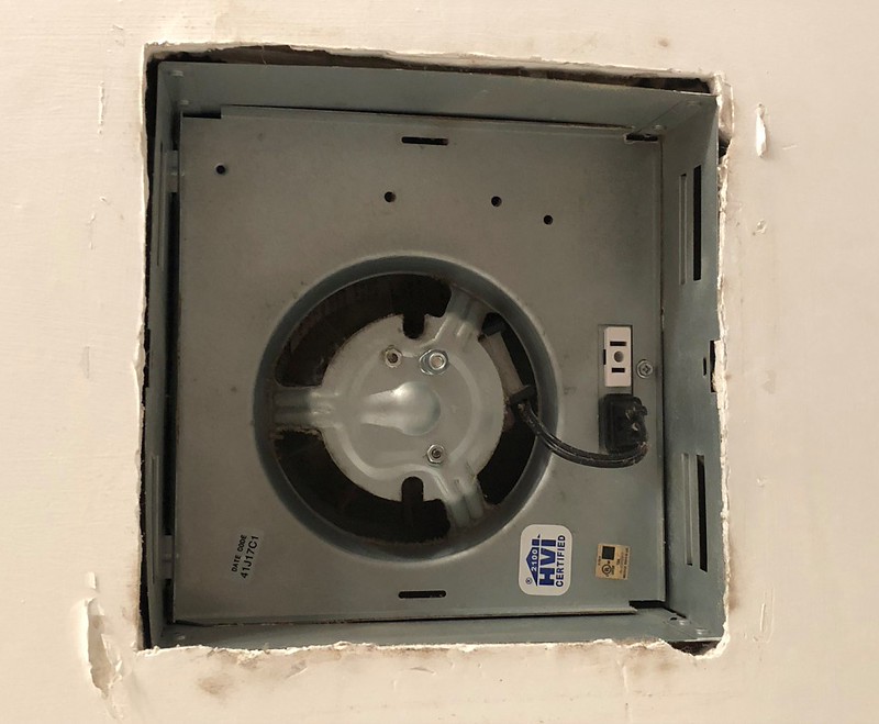 A bathroom exhaust fan housing with a small two-prong motor plug connected to an internal receptacle, real photo