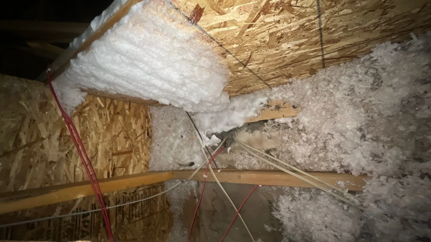A ceiling-mounted bathroom exhaust fan with a few water droplets forming on the grille in a small bathroom on a cold winter day, realistic home interior photo