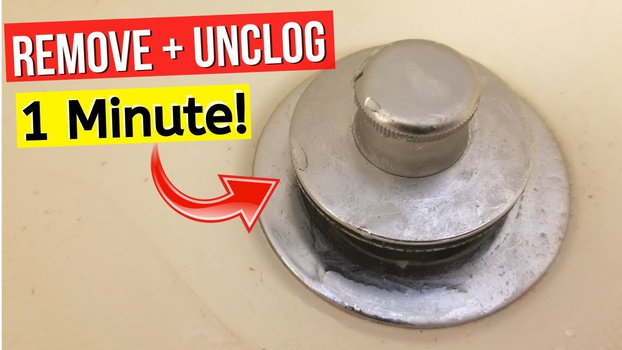 A close-up photo of a chrome bathtub drain stopper partially lifted with a small screwdriver and a folded towel protecting the tub surface