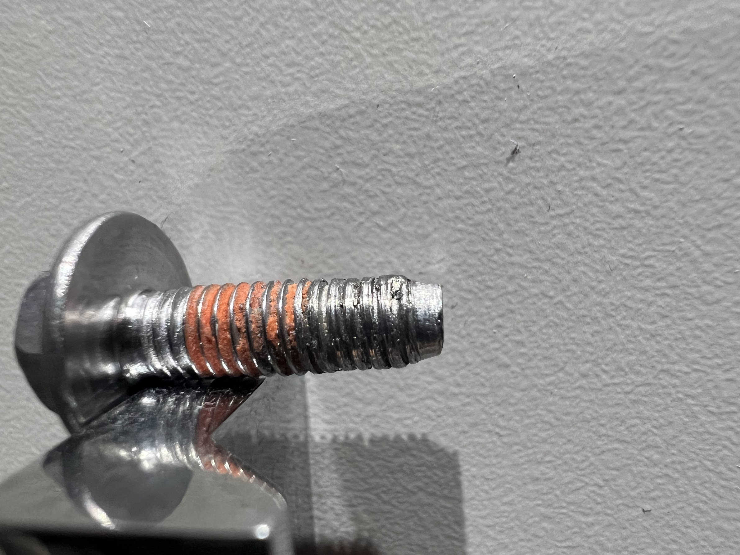 A close-up photo of a person tightening a dryer door hinge screw with a screwdriver while the dryer is unplugged