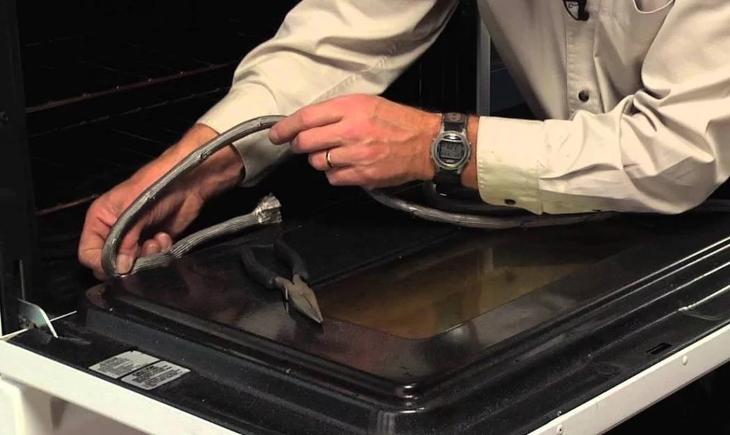 A close-up photo of a worn oven door gasket with cracking and flattened sections along the edge of the oven frame