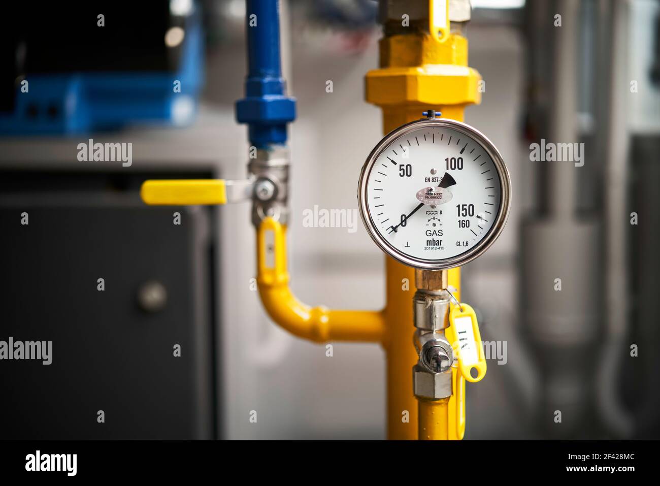 A close-up photograph of a residential gas boiler front panel showing the pressure gauge and control knobs in a basement utility room