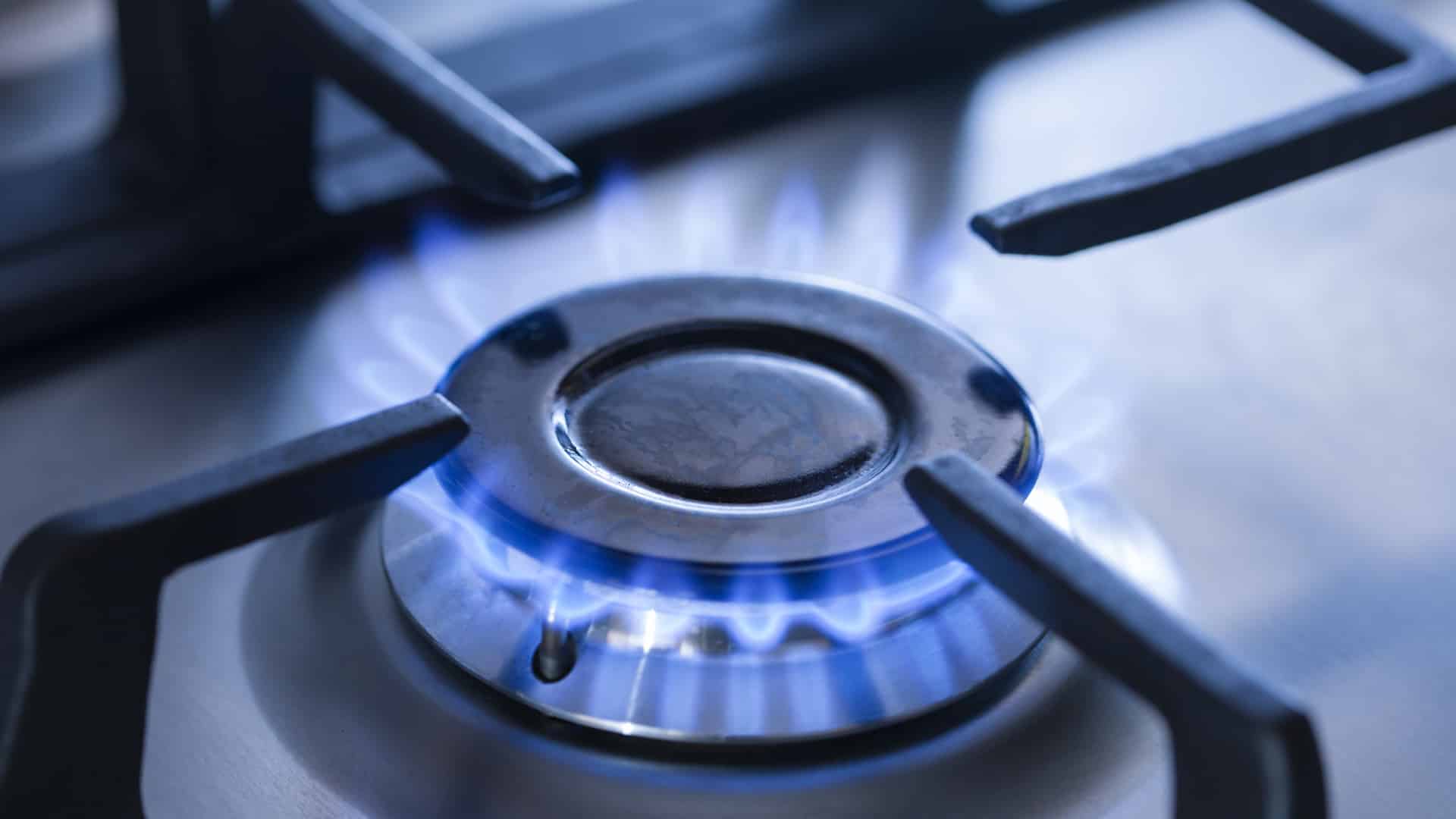 A close-up real photo of a modern gas range burner with the igniter electrode visible beside the burner cap on a kitchen stove