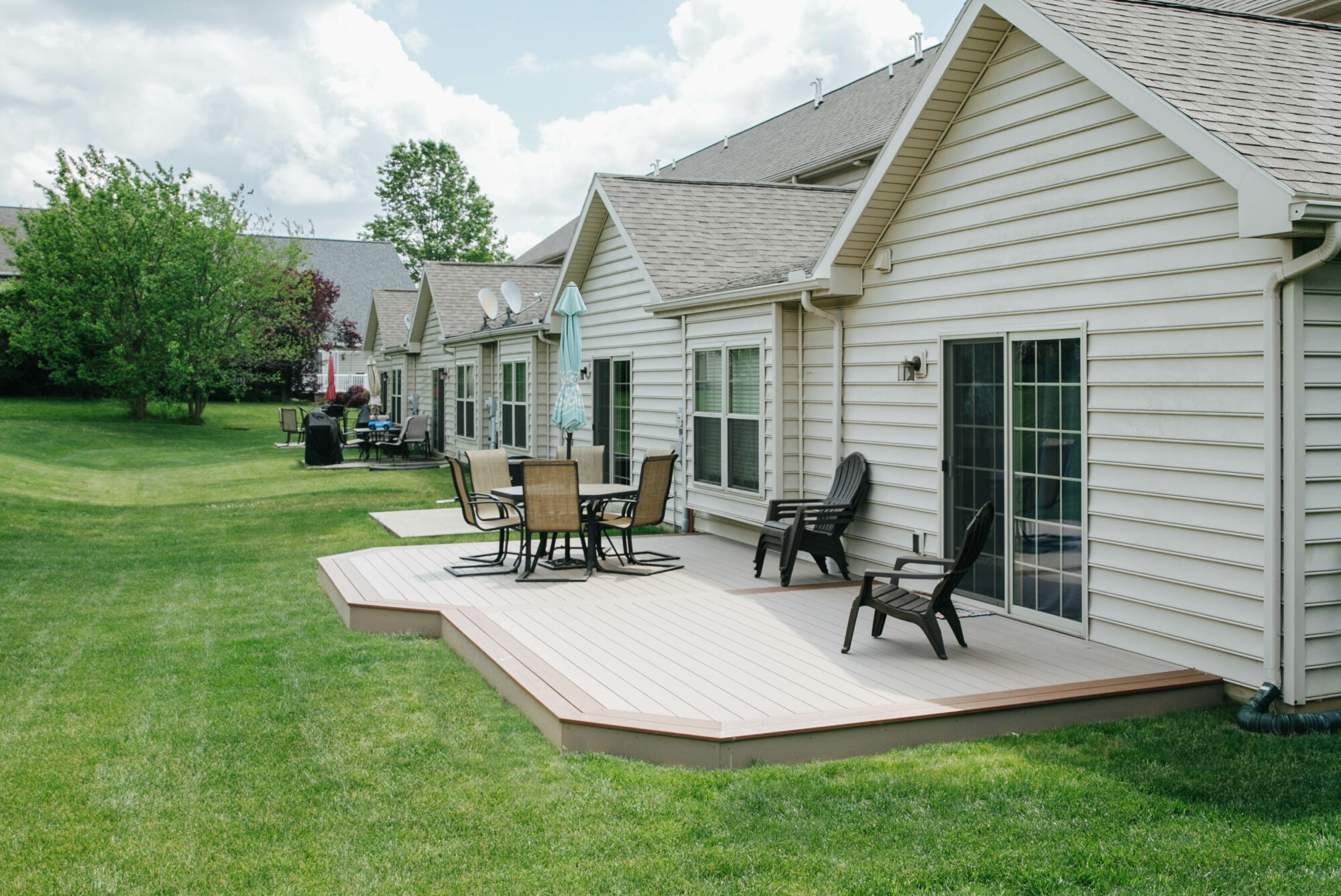 A freshly built small floating ground-level deck in a suburban backyard, pressure-treated wood framing with composite deck boards on top, afternoon sunlight, realistic photo