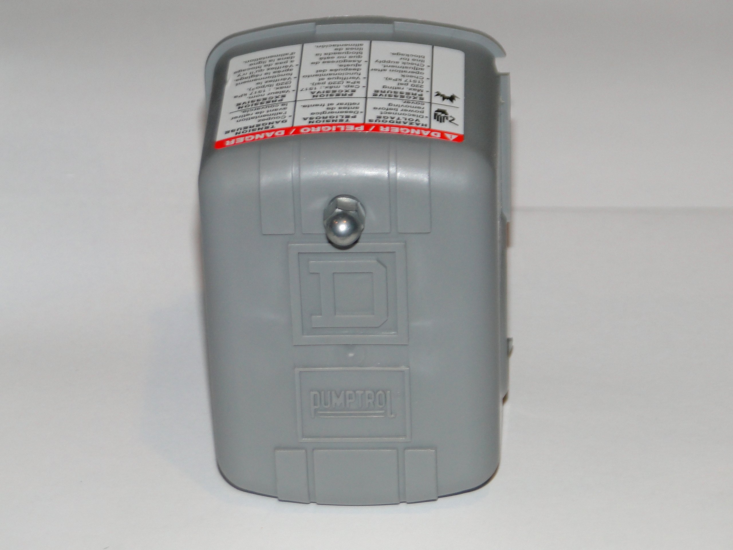 A gray metal well pump disconnect box mounted on a wall near exposed plumbing lines, with the cover closed
