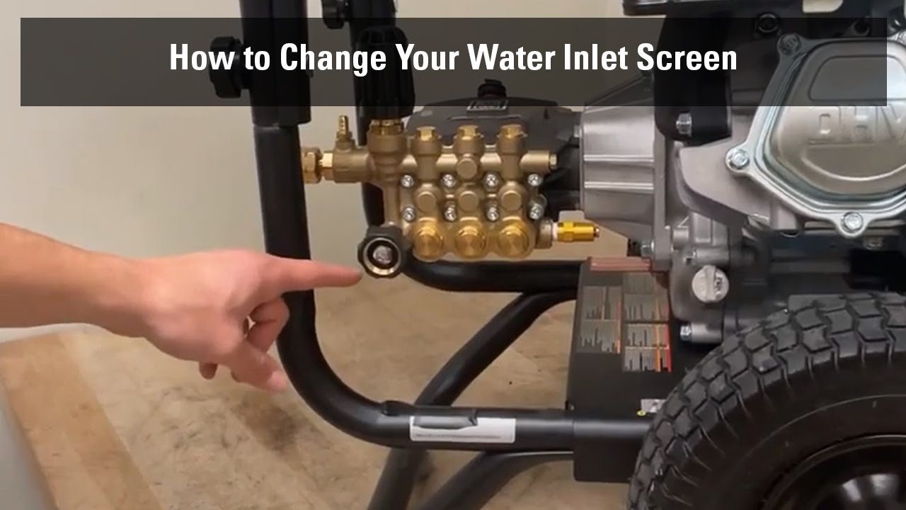 A hand rinsing a small mesh inlet screen filter from a pressure washer under running tap water, with the pump connection visible nearby