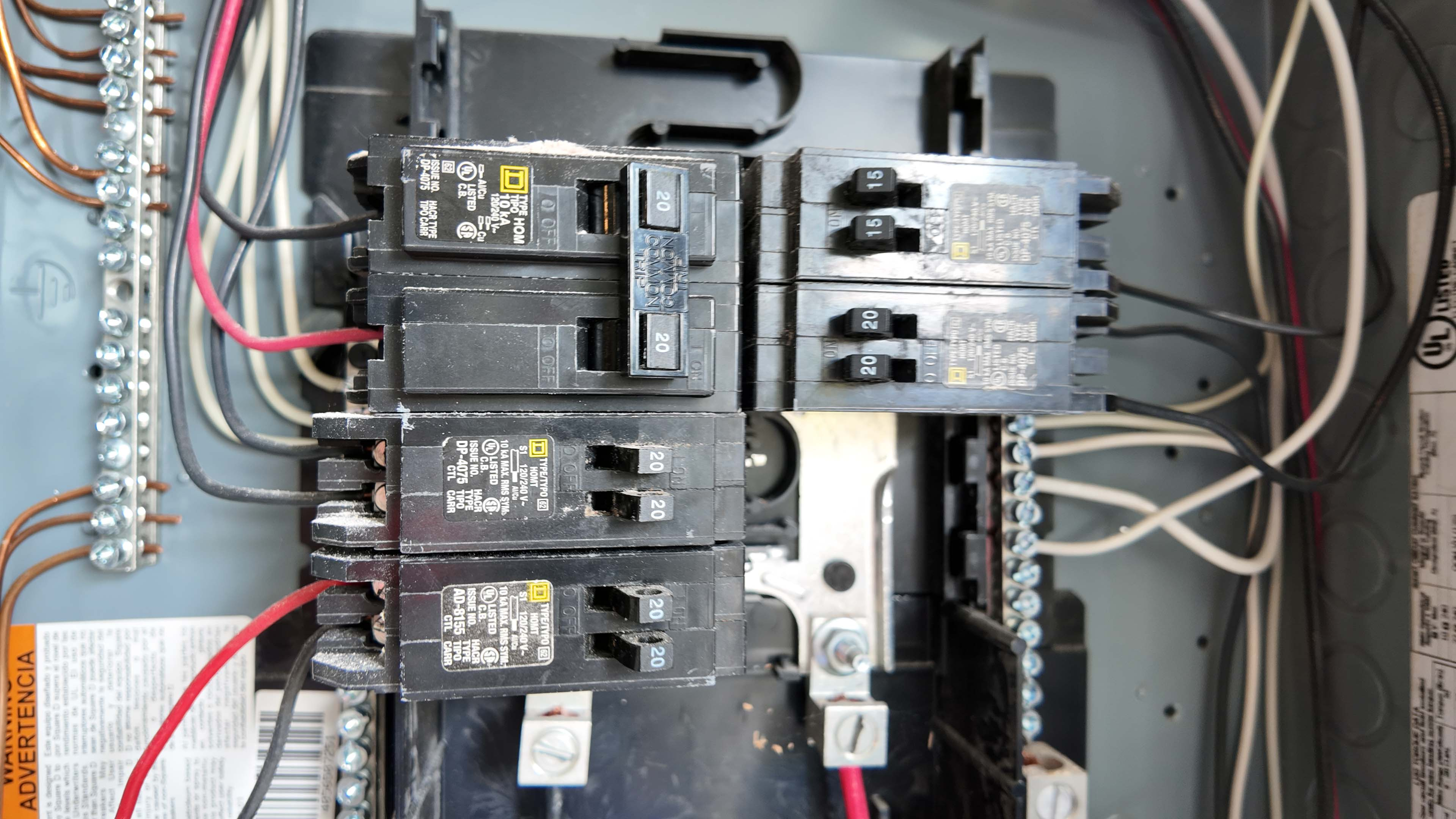 A homeowner cautiously standing back from a residential breaker panel in a basement, showing concern, realistic photo with normal indoor lighting