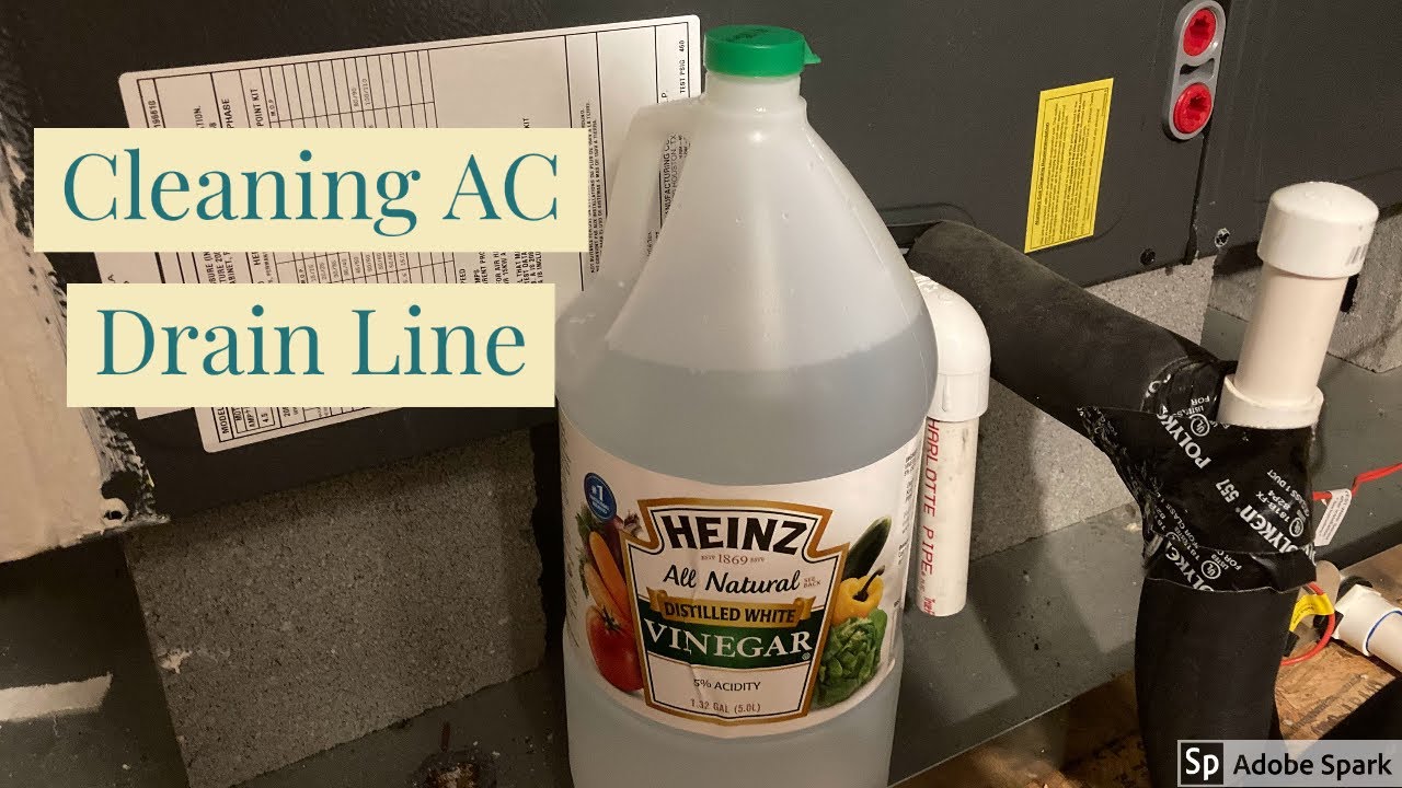 A homeowner pouring white vinegar from a measuring cup into a PVC condensate drain cleanout tee next to an indoor air handler, close-up real photo