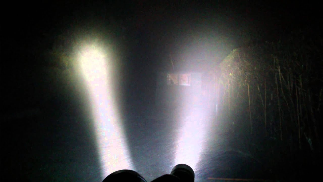 A homeowner standing indoors at night shining a small flashlight across a foggy double-pane window to reveal haze trapped between panes