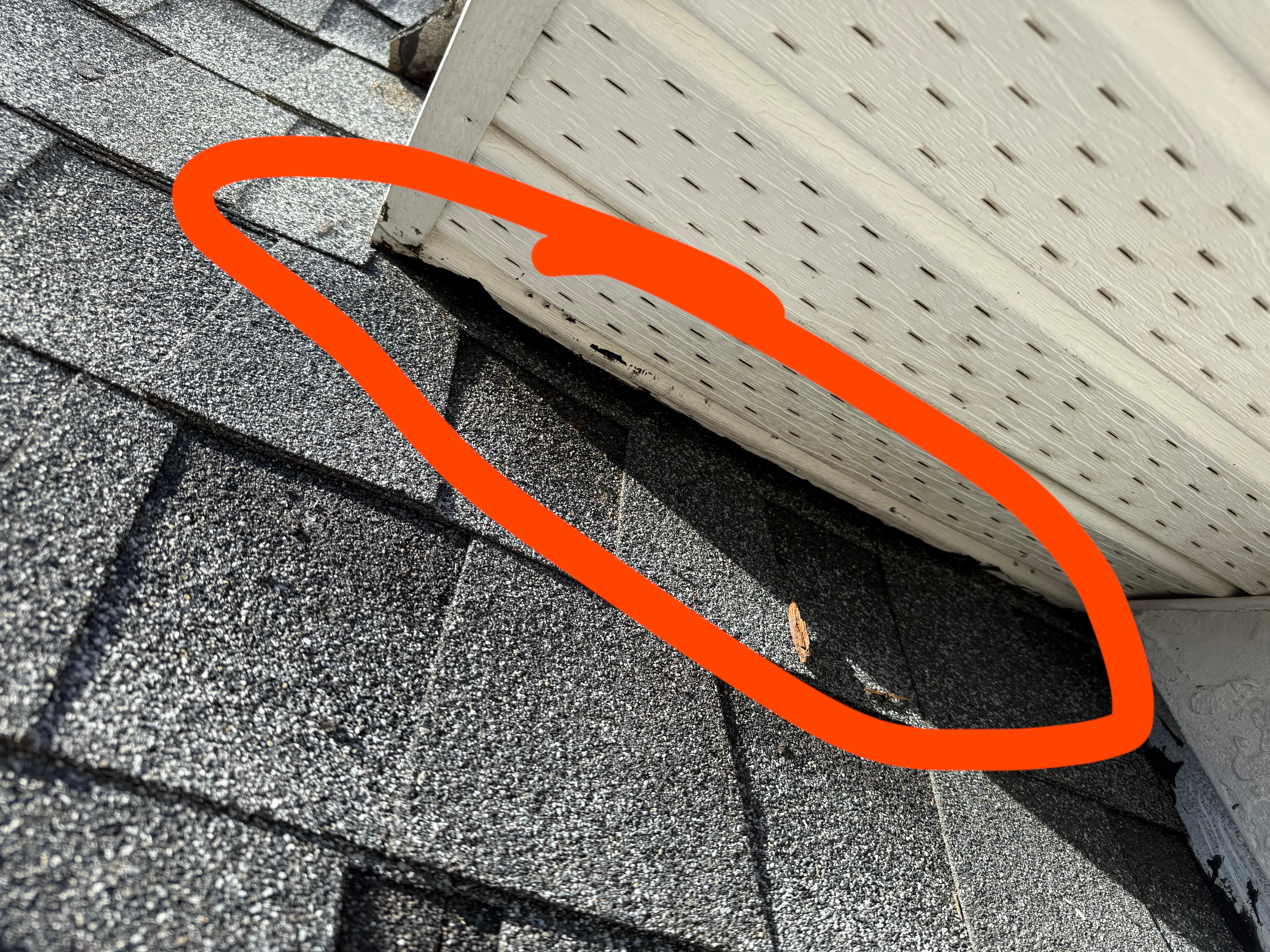 A homeowner wearing a headlamp inspecting a soffit and fascia gap near the roofline at dusk, real exterior home photo