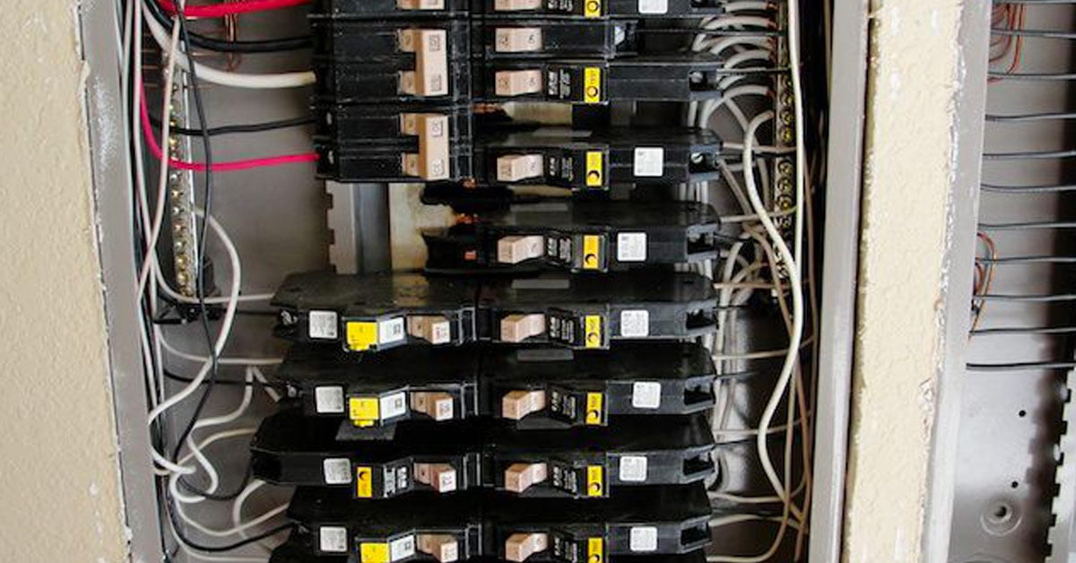 A homeowner’s hand resetting an AFCI breaker in a residential electrical panel with several labeled breakers, realistic indoor photo