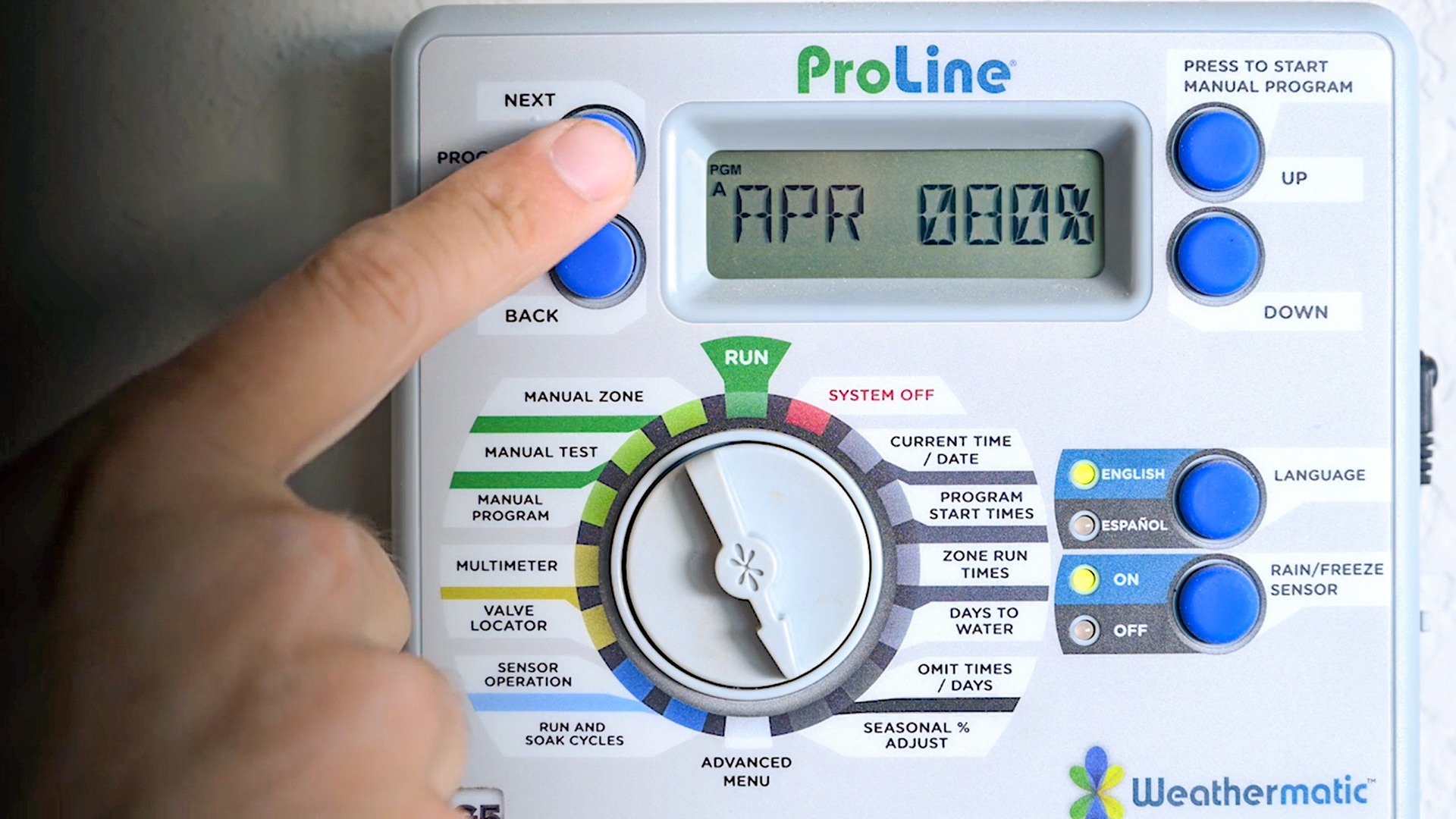 A homeowner’s hand turning the dial on an irrigation controller and pressing buttons to set a watering schedule, realistic close-up photo