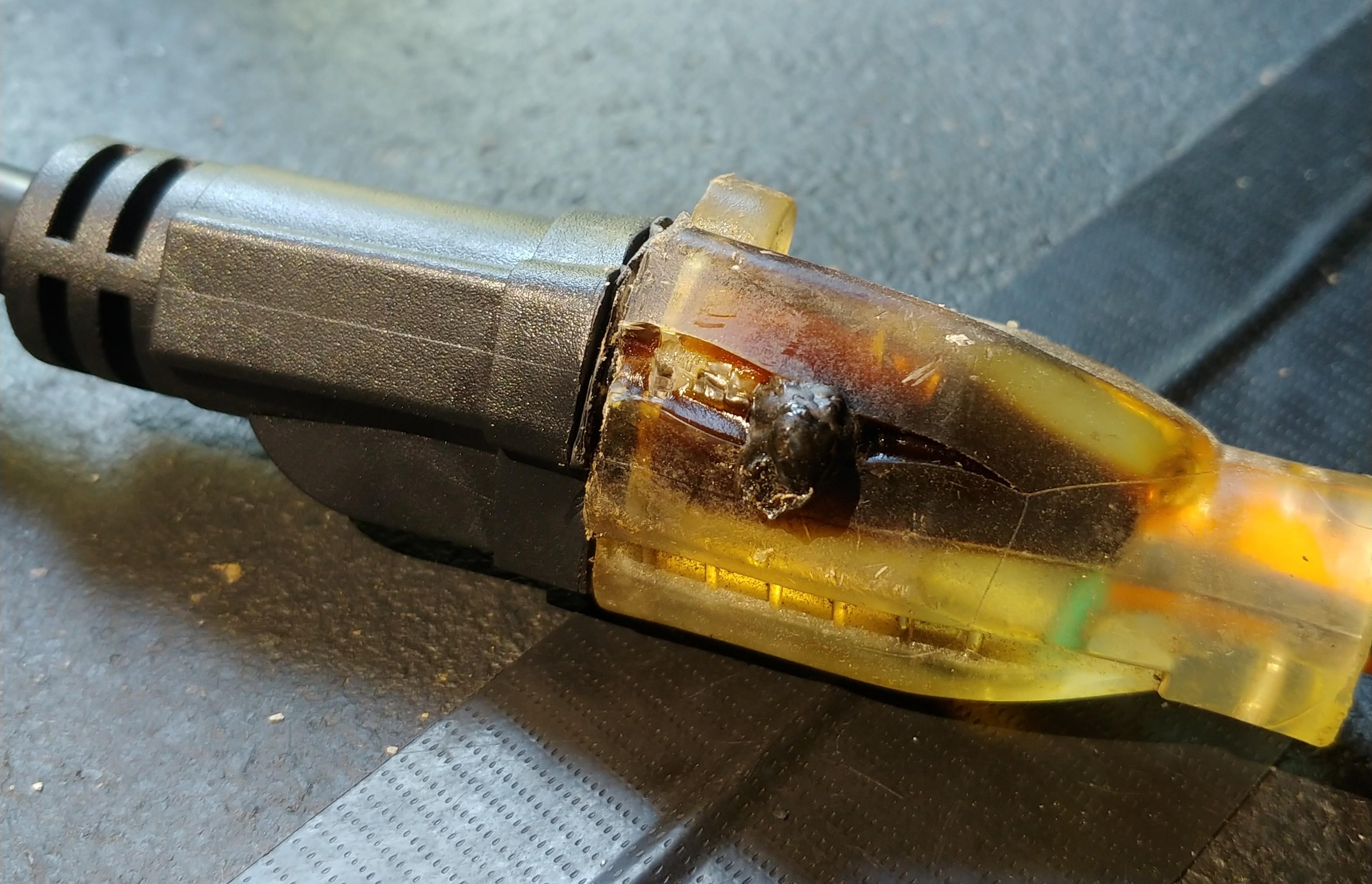 A microwave power cord plug with visible heat damage and darkened plastic near the prongs