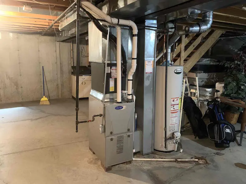 A modern gas furnace installed in a residential basement mechanical room with ductwork and a return air filter slot visible, natural indoor lighting, photorealistic