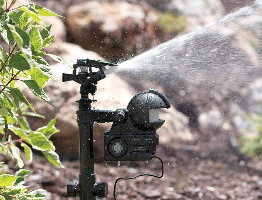 A motion-activated sprinkler spraying water in a backyard at night near a garden bed, realistic home photo