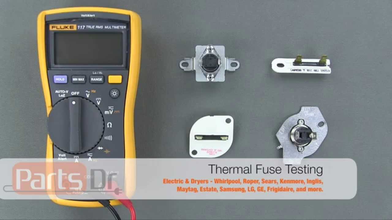 A person holding multimeter probes on the terminals of a dryer thermal fuse during a continuity test in a laundry room