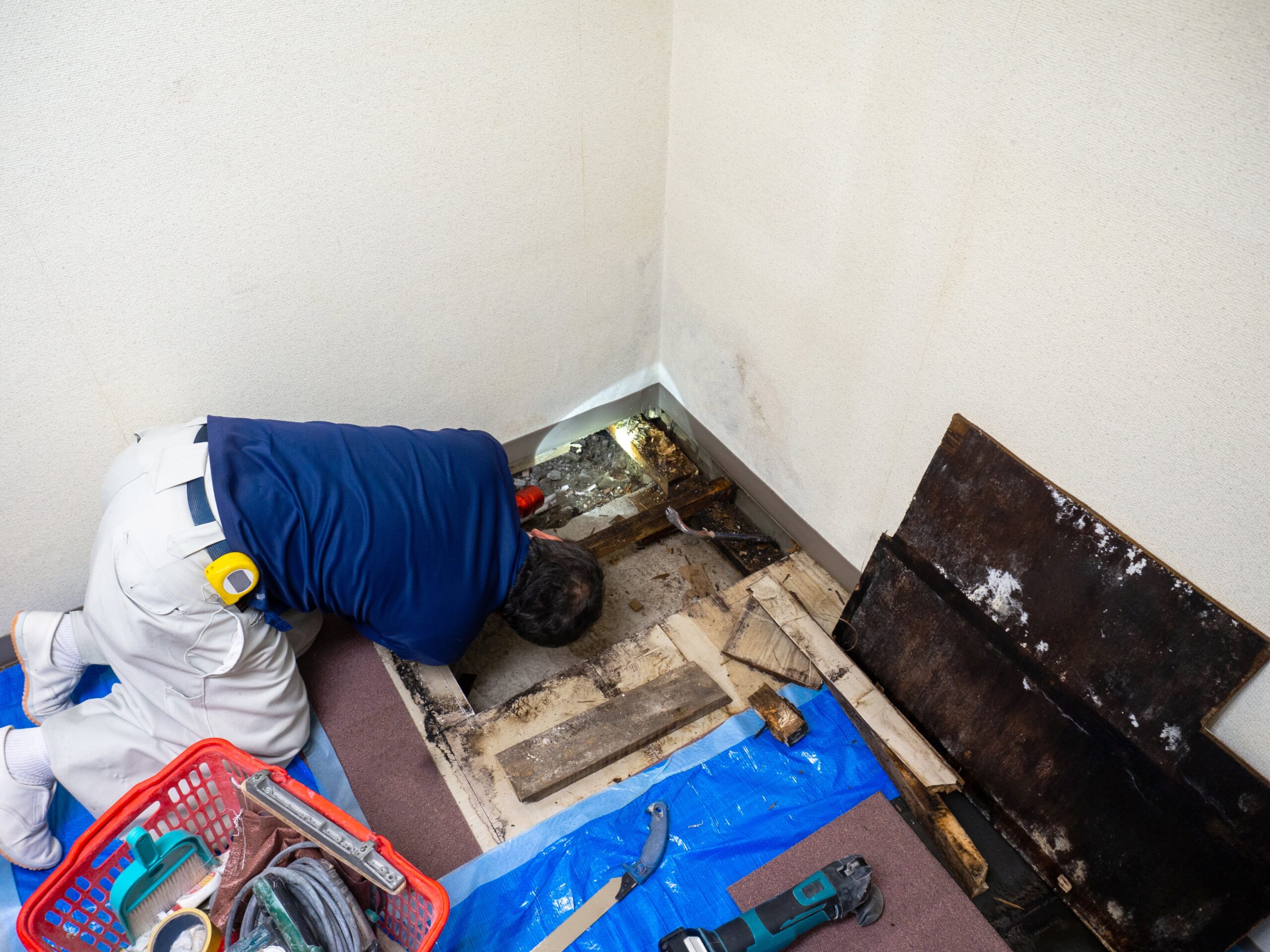 A person placing the back of their hand on a tile floor to check an unusual warm area near the center of a room, realistic home photo