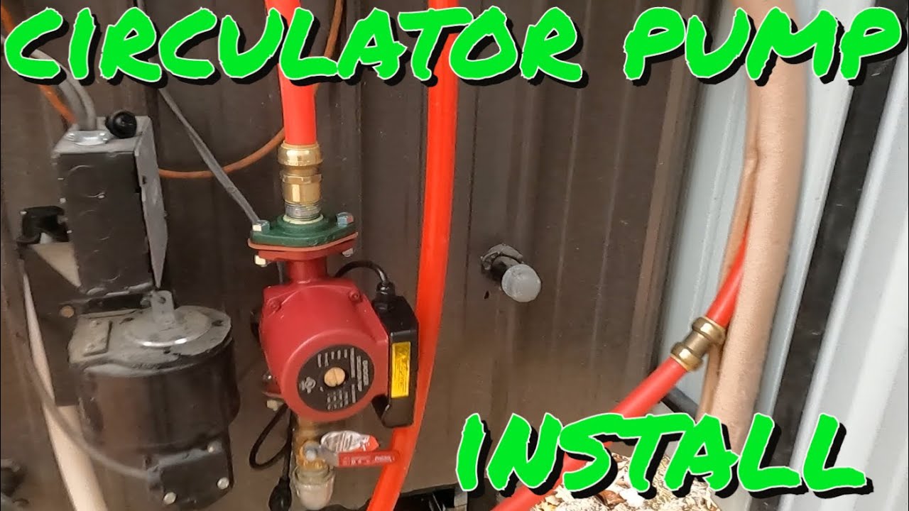 A photograph of a green hydronic circulator pump mounted between copper pipes next to a residential boiler
