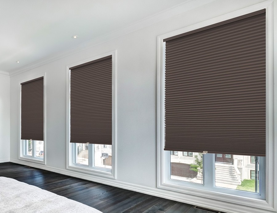 A real bedroom window with blackout cellular shades installed inside the window frame, showing a clean top headrail and evenly spaced pleats