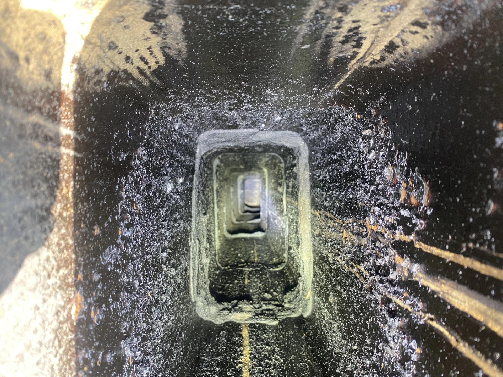 A real close-up photo looking into a chimney flue where shiny black glazed creosote coats the inner surface like hardened glass