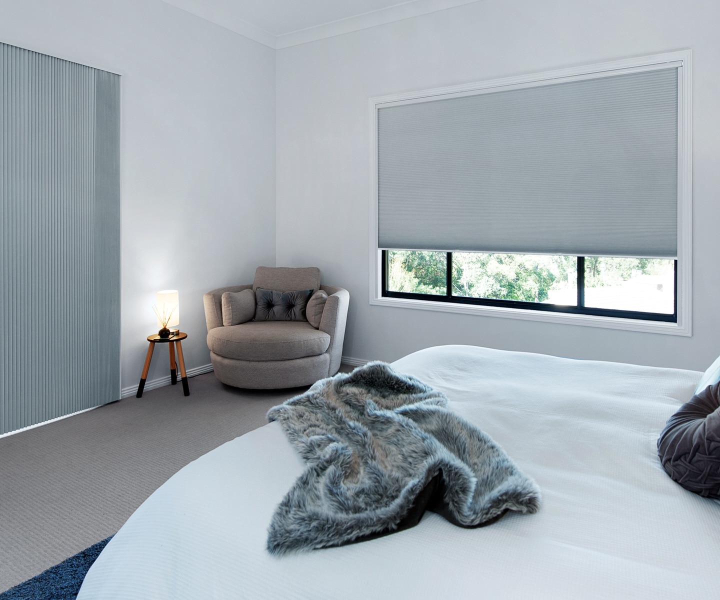 A real home bedroom window with blackout cellular beehive blinds fully lowered inside the window frame, showing a snug fit at the top rail