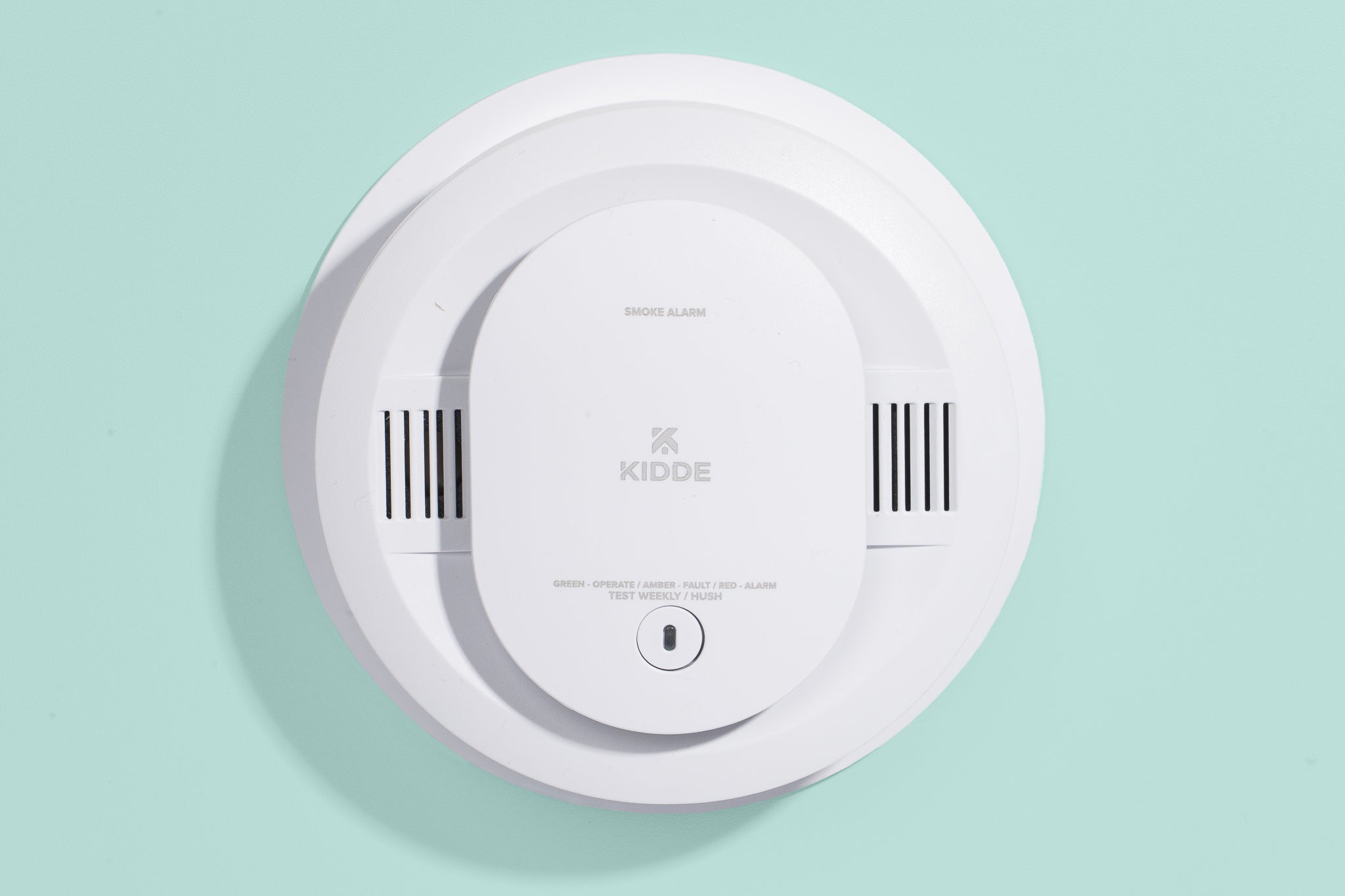 A real kitchen ceiling with a smoke alarm mounted near a stove and a stainless range hood, showing typical placement that can cause cooking false alarms