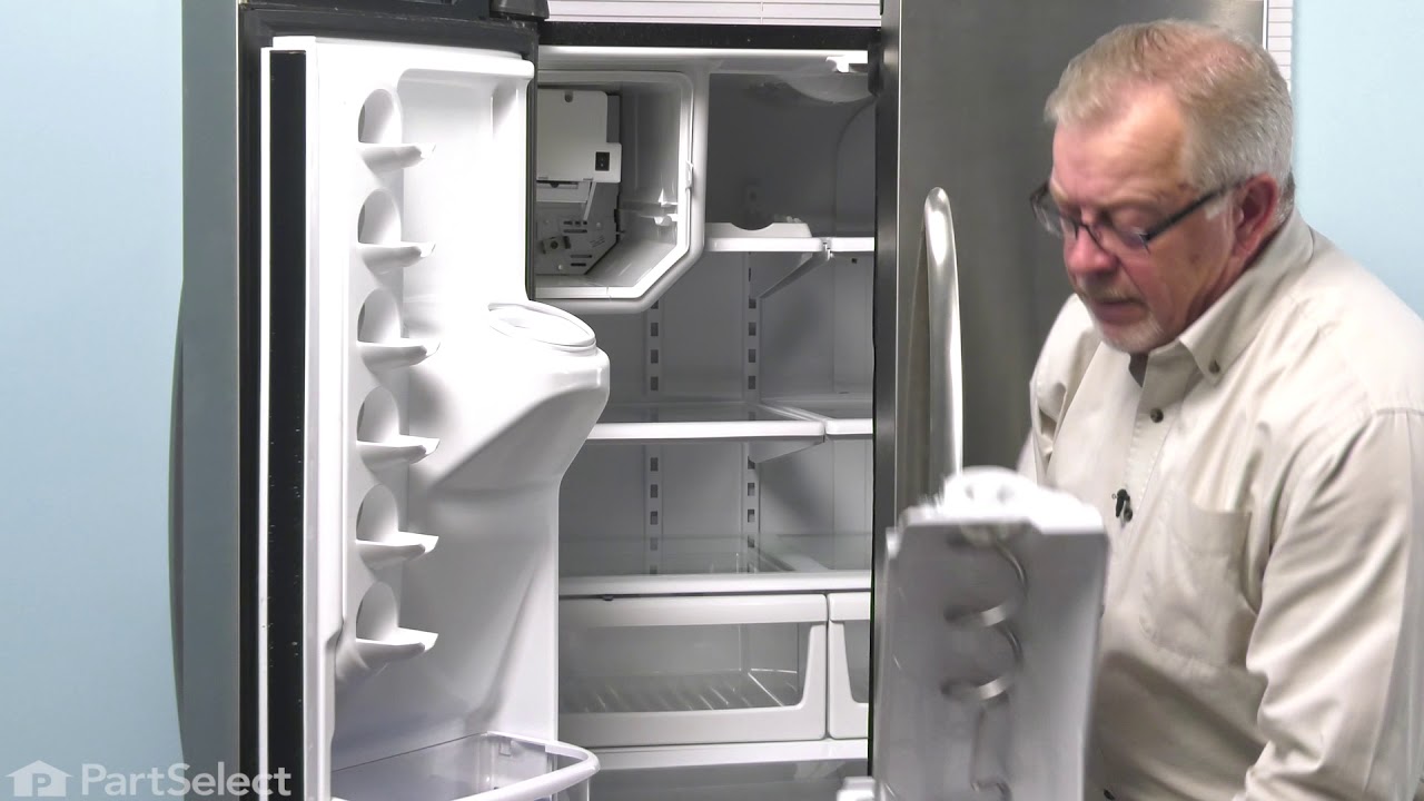A real kitchen freezer drawer pulled open with a cloudy plastic ice bin visibly frosted and stuck in place, natural indoor lighting, close-up photo