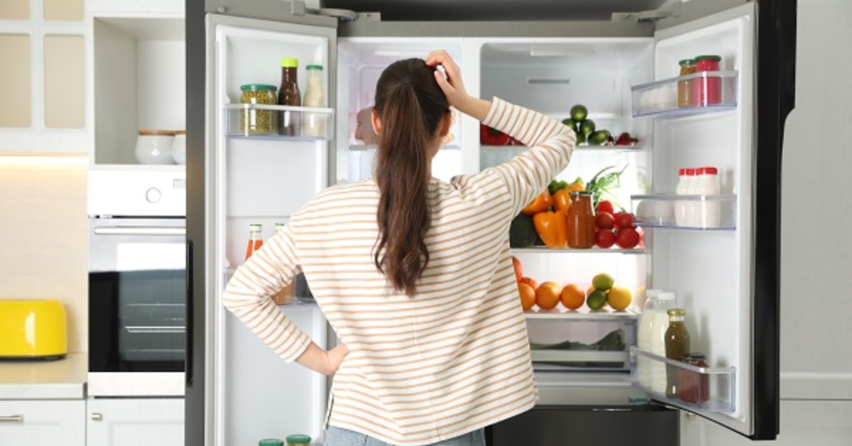 A real kitchen photo of a top-freezer refrigerator with the freezer door open and the refrigerator door open, showing shelves and vents where cold air moves between compartments