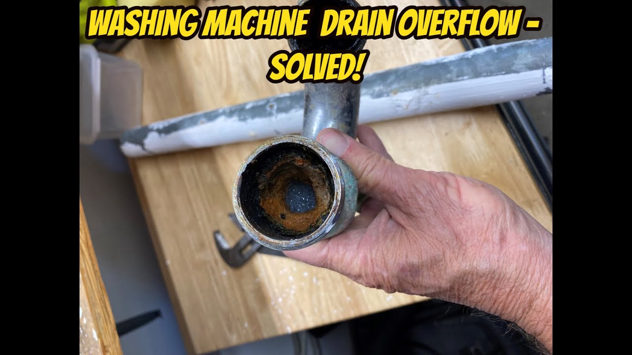 A real laundry room with a washing machine draining into a standpipe that is overflowing slightly at the top, water splashing near the drain opening