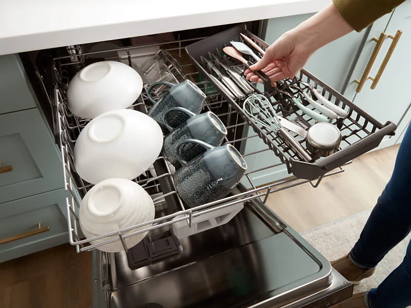 A real photo looking into an open dishwasher showing properly loaded dishes with an unobstructed detergent dispenser on the door