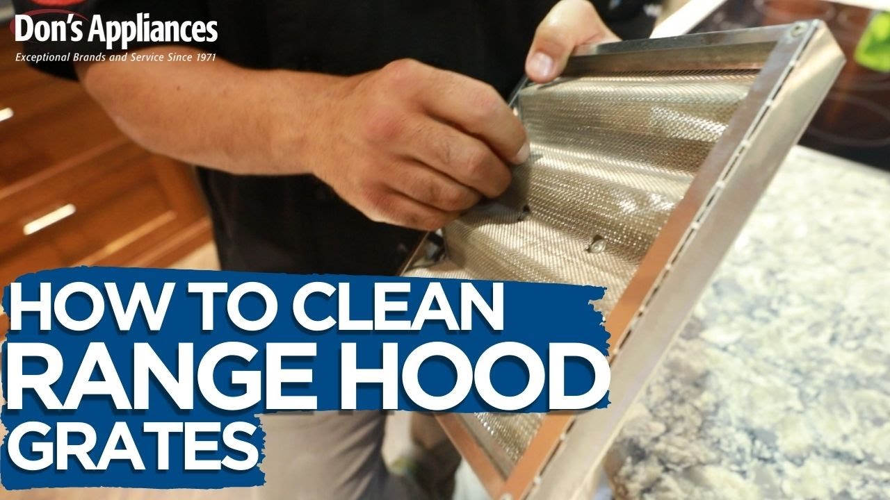 A real photo of a cylindrical range hood blower wheel removed from a hood and being scrubbed with a brush on a workbench