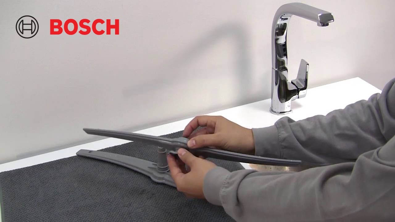 A real photo of a dishwasher lower rack with a large baking sheet positioned in a way that blocks the lower spray arm from spinning