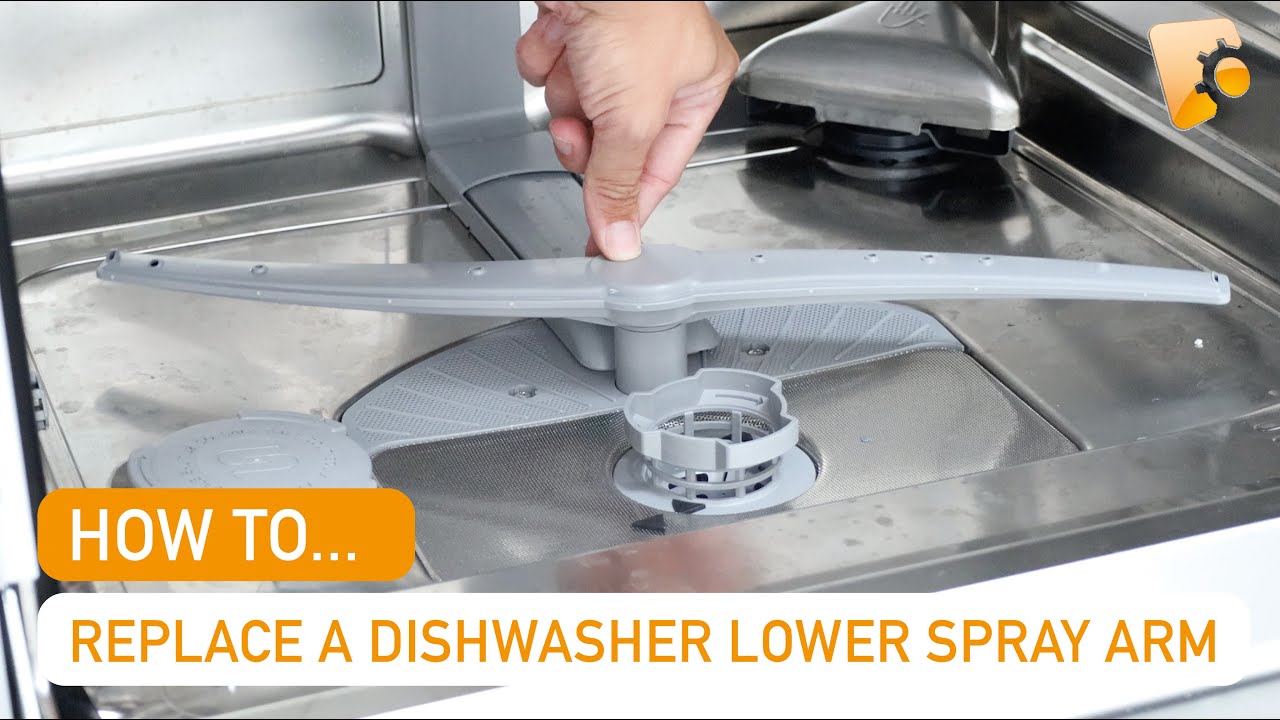 A real photo of a dishwasher lower spray arm removed and resting on a kitchen counter next to a sink, with visible mineral buildup around the spray holes