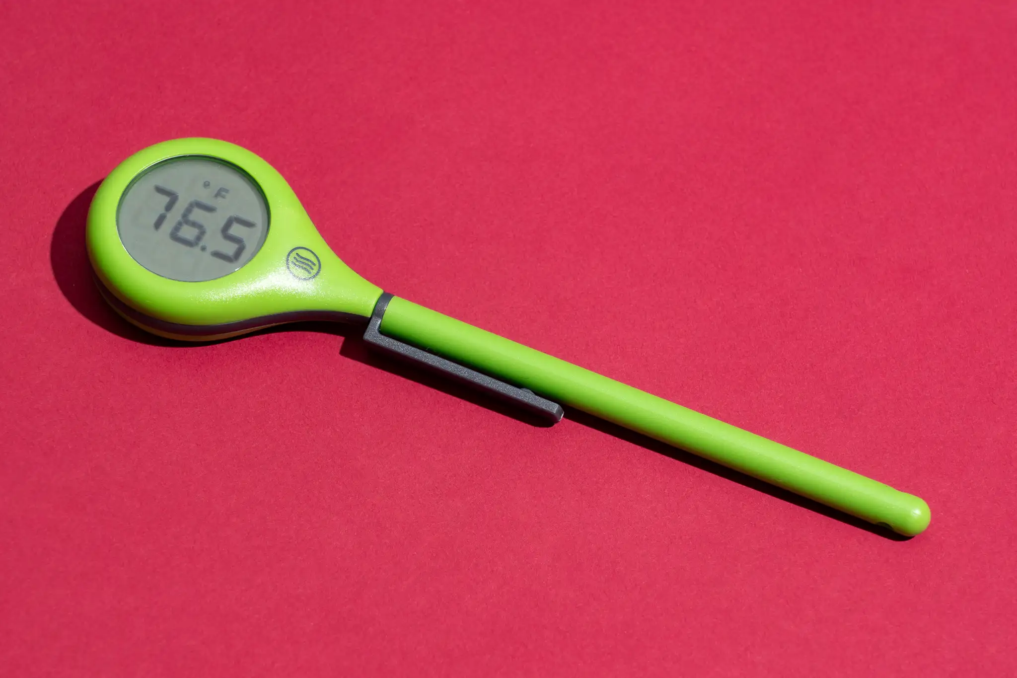 A real photo of a kitchen sink with hot water running into a cup while a small thermometer measures the water temperature