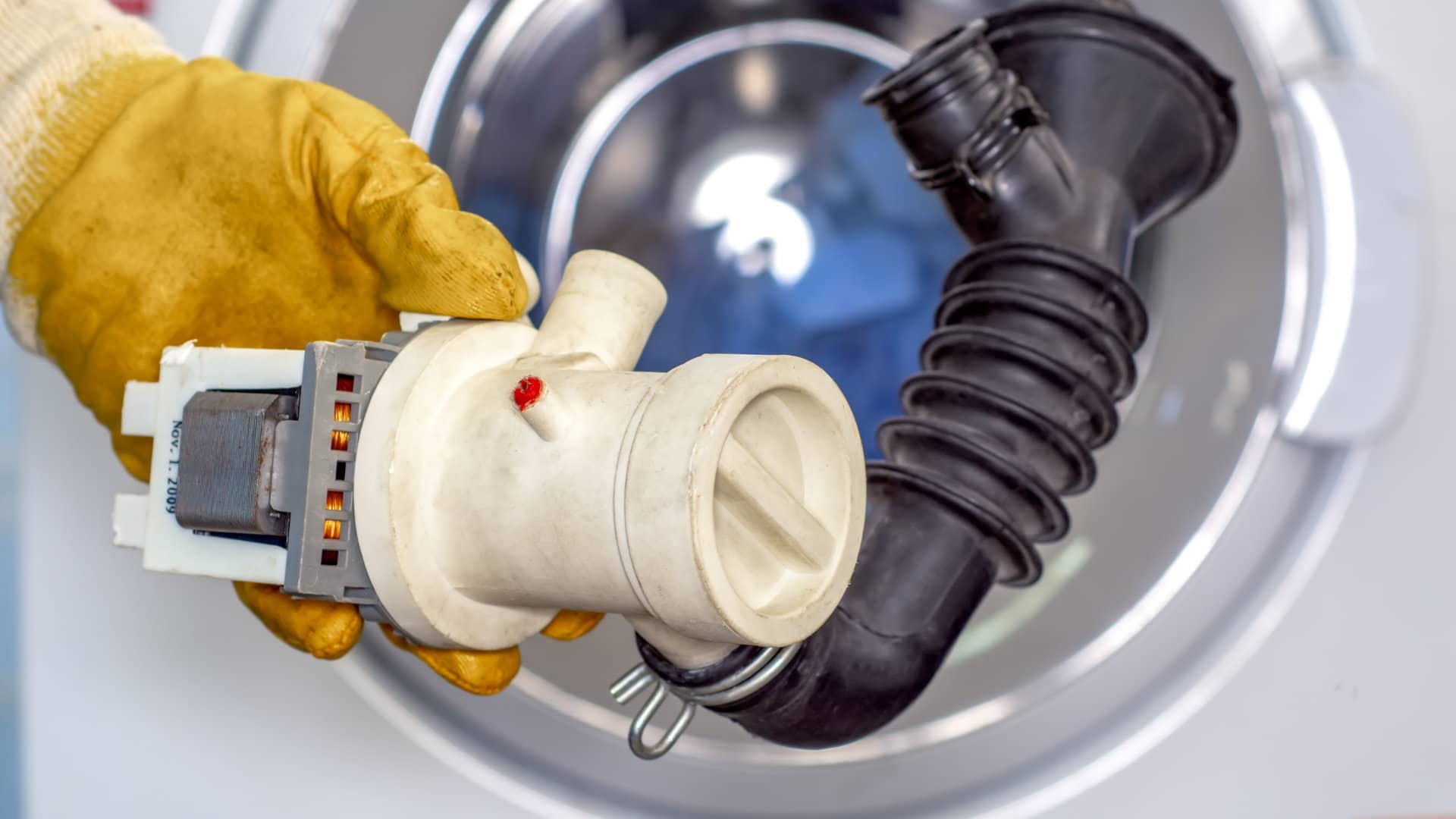 A real photo of a washer drain pump filter on a towel with coins, lint, and small debris removed from the trap