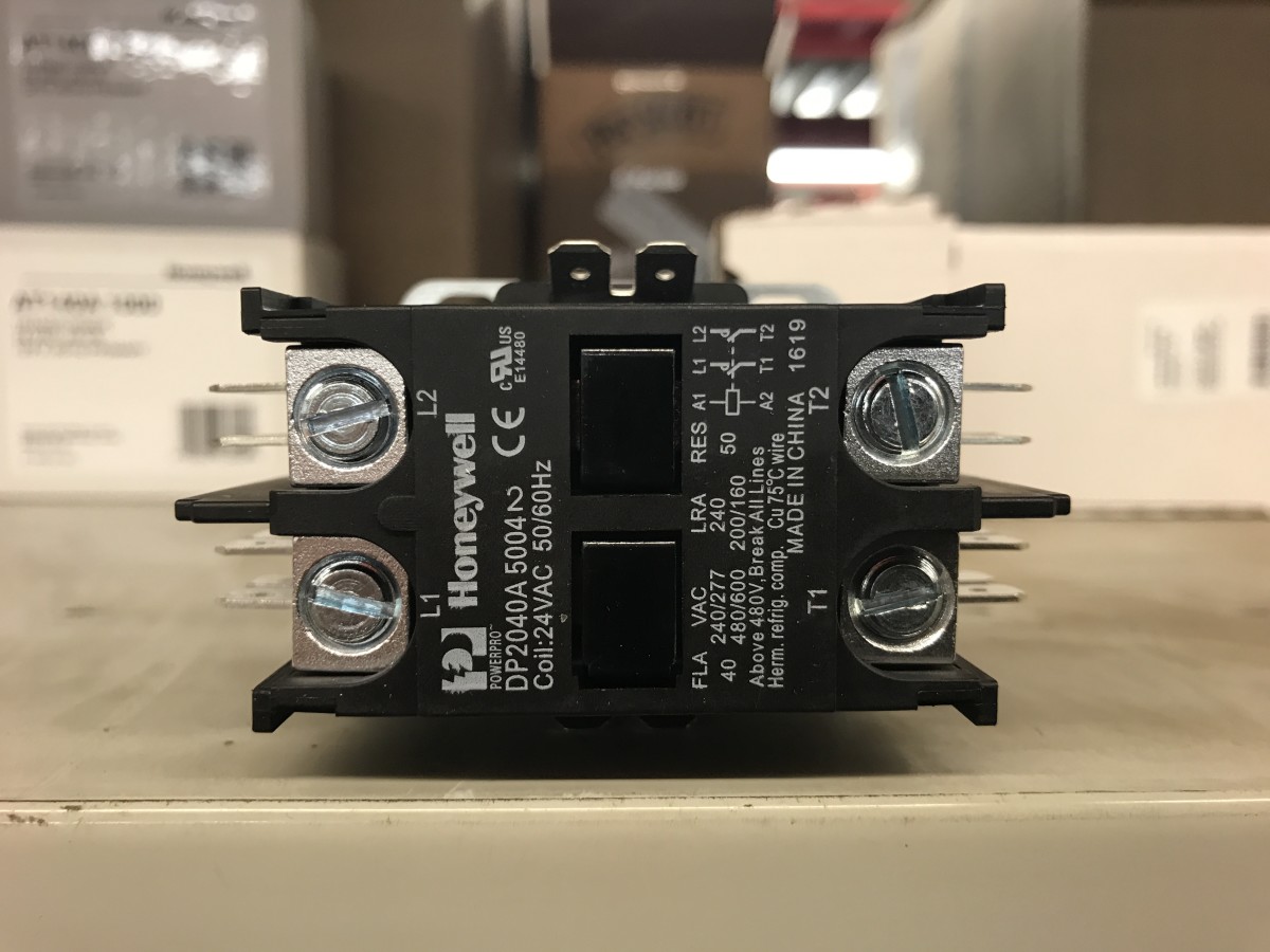 A real photo of an HVAC technician-style view inside an outdoor AC condenser electrical compartment showing a contactor and wiring