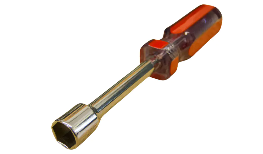 A real photo of basic dryer repair tools on a workbench, including a nut driver, screwdrivers, needle-nose pliers, and a small vacuum hose attachment