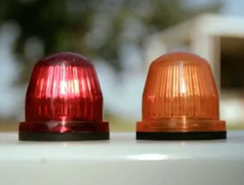 A real septic alarm control panel mounted on a basement wall with a red warning light illuminated and a silence button visible, indoor home utility room photo