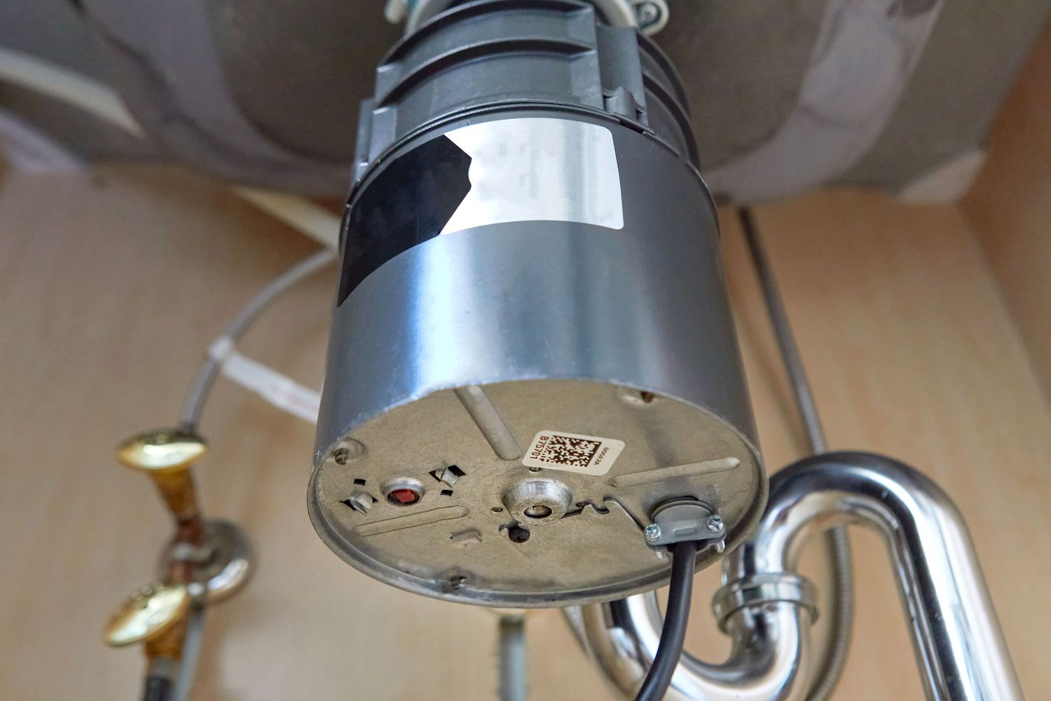A real under-sink photo showing the bottom of a garbage disposal with a red reset button visible near the center