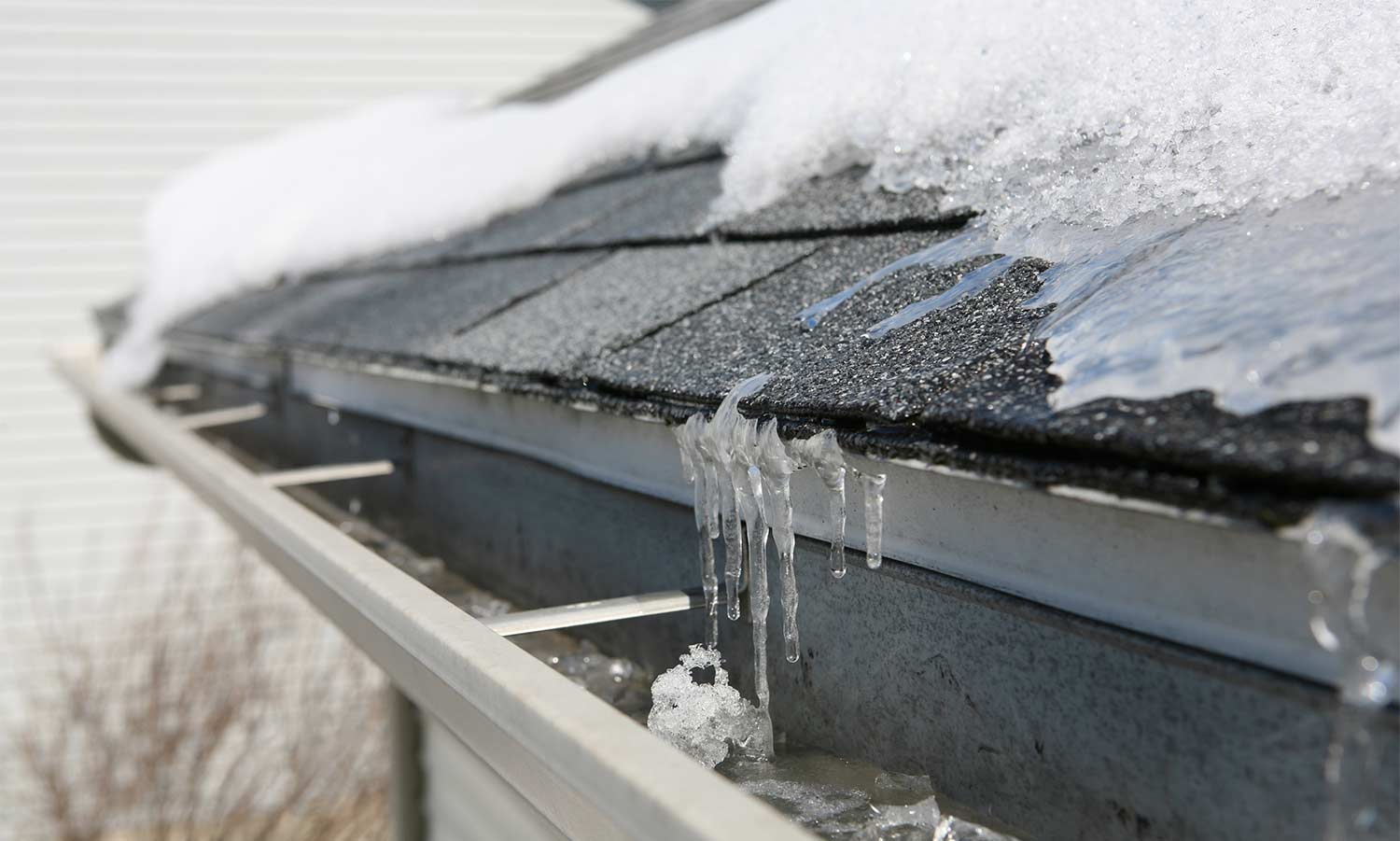 A real winter photo of a roof with snow higher up and a clear icy band at the eaves where meltwater has refrozen