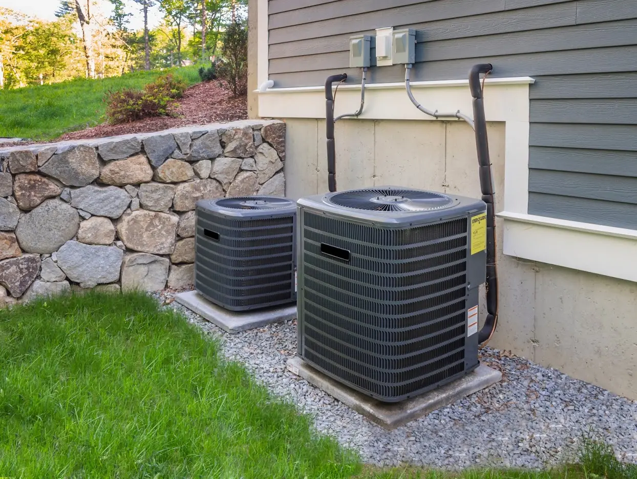 A residential central air conditioner outdoor condenser unit sitting on a concrete pad beside a home, daylight, clear view of the unit cabinet and top fan grille