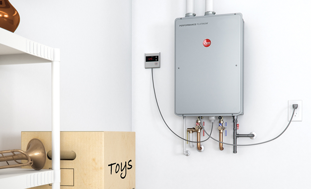 A residential tankless water heater mounted on a basement wall with visible water lines and a gas line, photographed in a real home