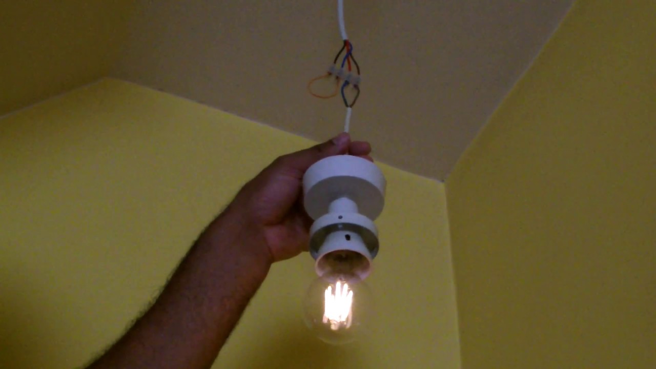 A single LED bulb in a ceiling fixture glowing faintly in a dim hallway even though the wall switch is turned off, realistic home interior photograph