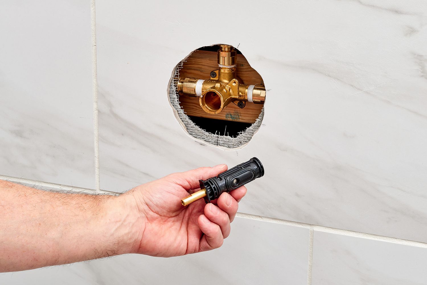 A single-handle shower with the handle and trim removed, exposing the retaining clip and cartridge stem in the valve
