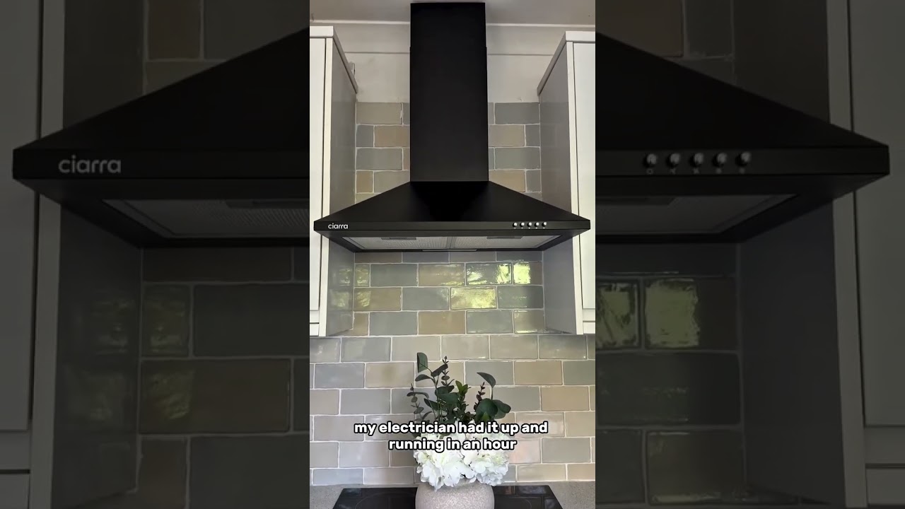 A stainless steel wall canopy range hood mounted above a kitchen range with the filters removed, showing the grease-laden underside and blower intake, real indoor photo