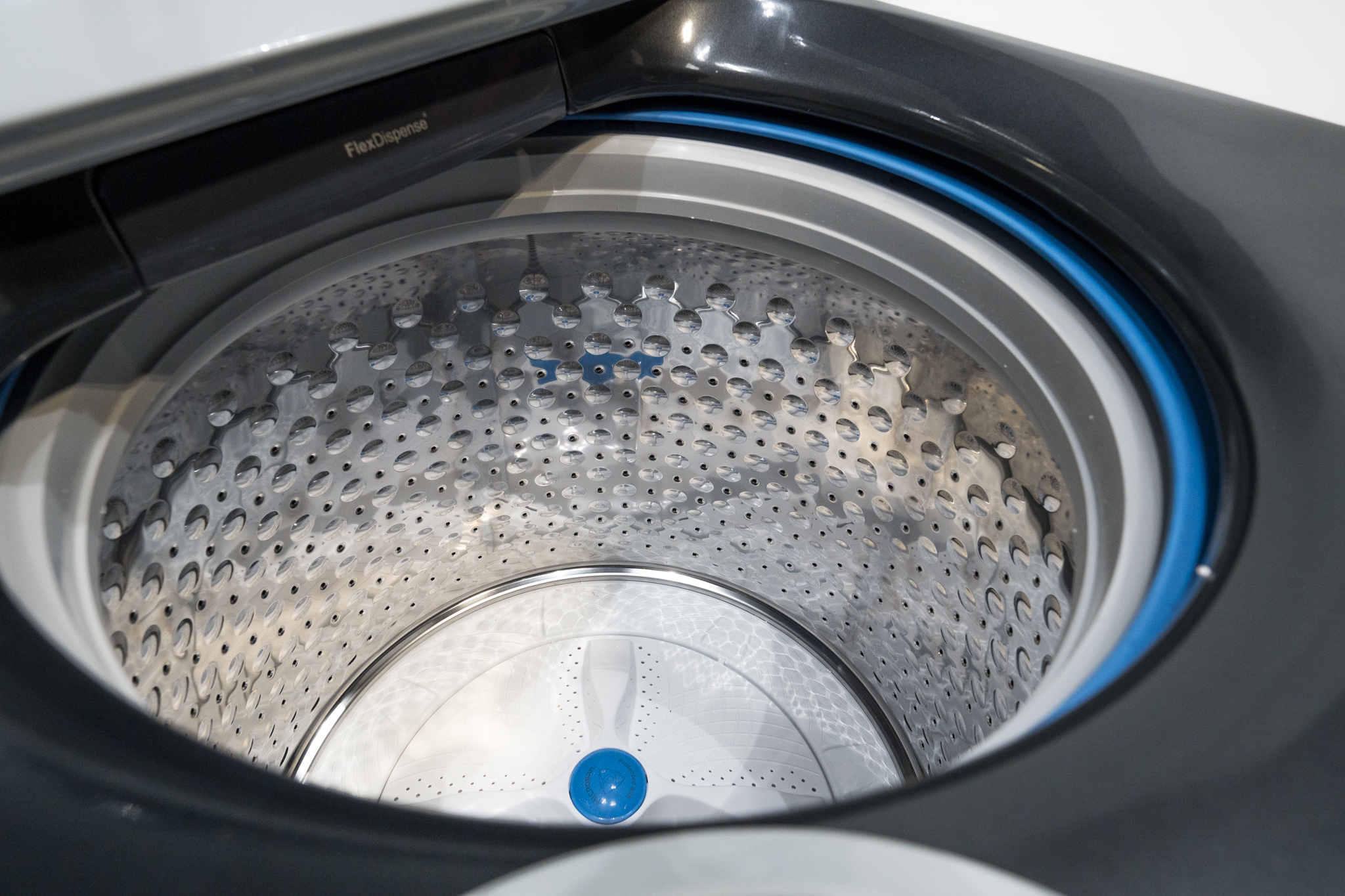 A top-loading washer tub with a heavy towel load piled to one side, showing an unbalanced distribution inside the drum