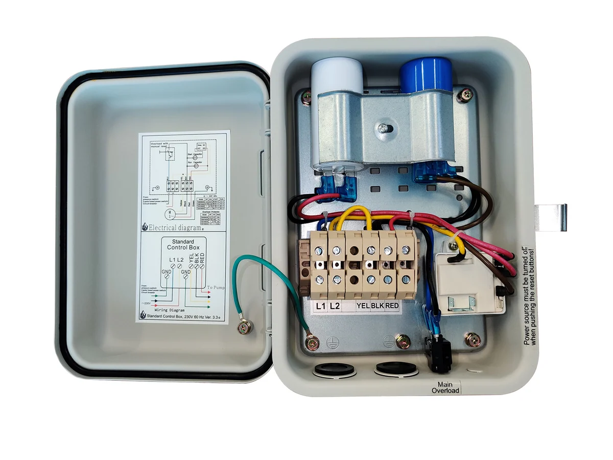 A wall-mounted gray submersible well pump control box installed near a blue pressure tank in a utility room