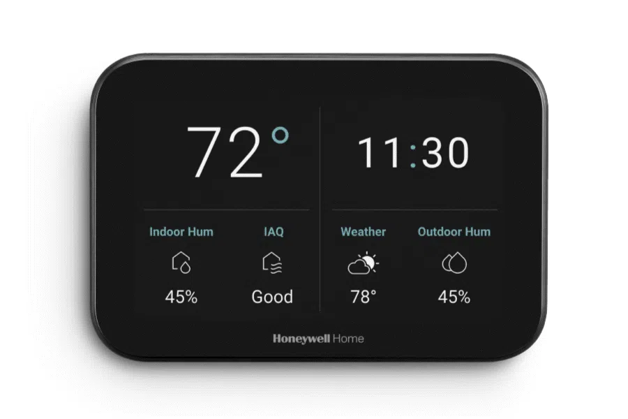 A wall-mounted smart thermostat displaying the current indoor temperature and a cooling setpoint in a hallway