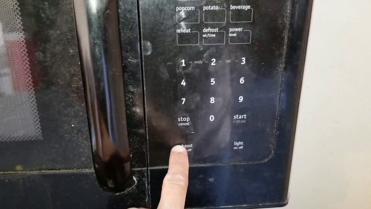 An over-the-range microwave above a stove with visible steam rising from a pot on the cooktop