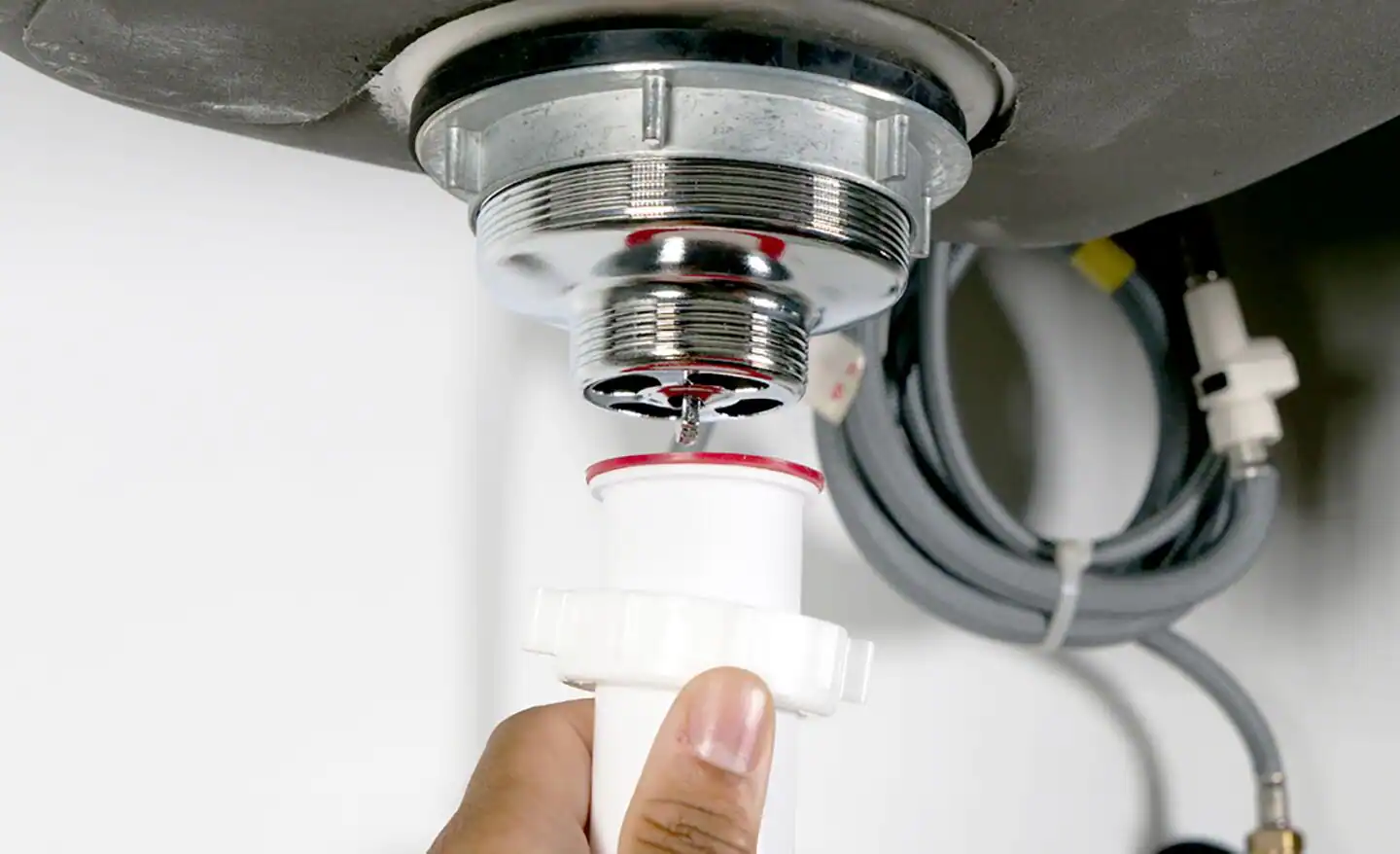 Bucket placed beneath a kitchen sink P-trap while the slip nuts are loosened for removal